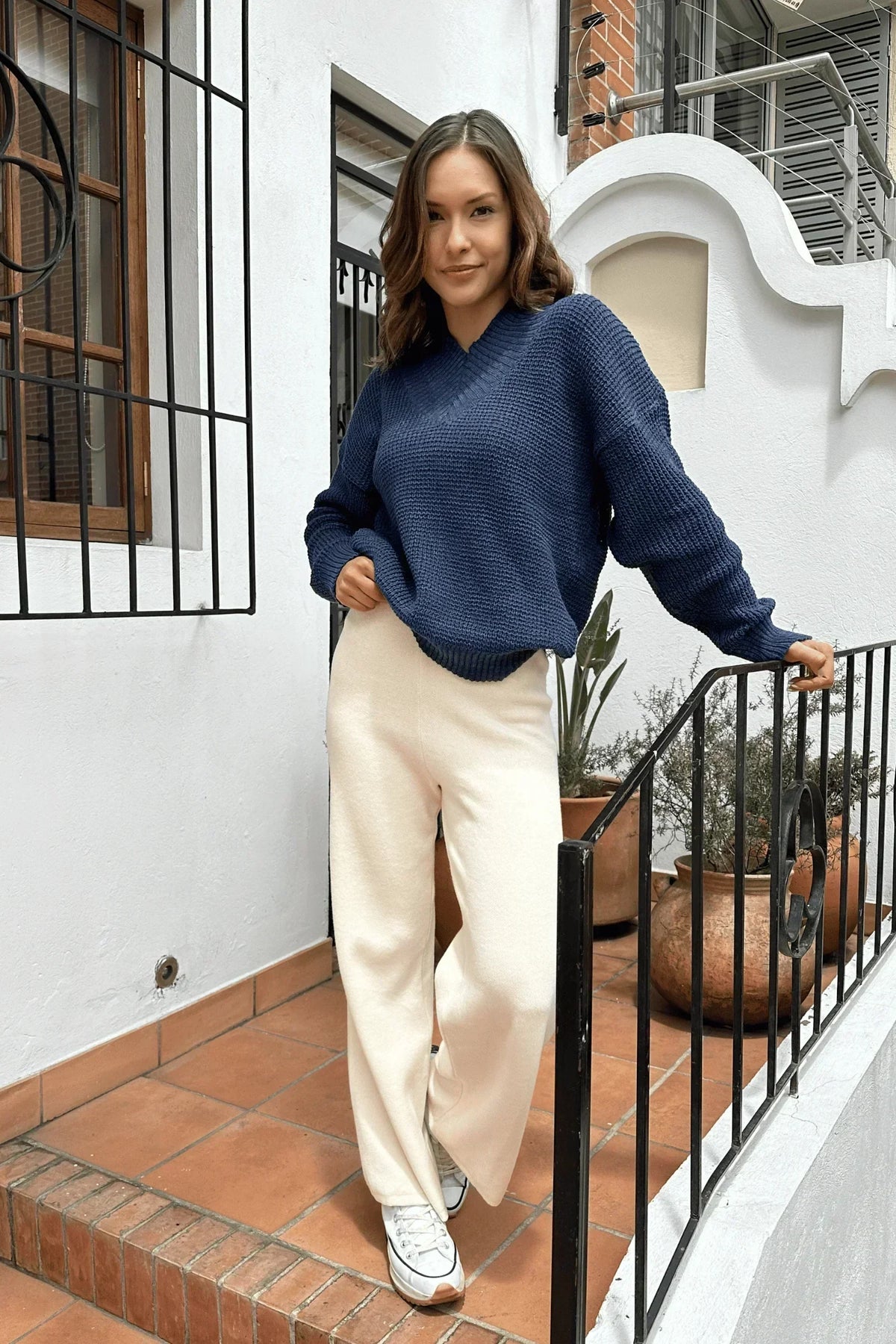 Mujer con suéter azul tejido y pantalón blanco, estilo casual y cómodo para mujer