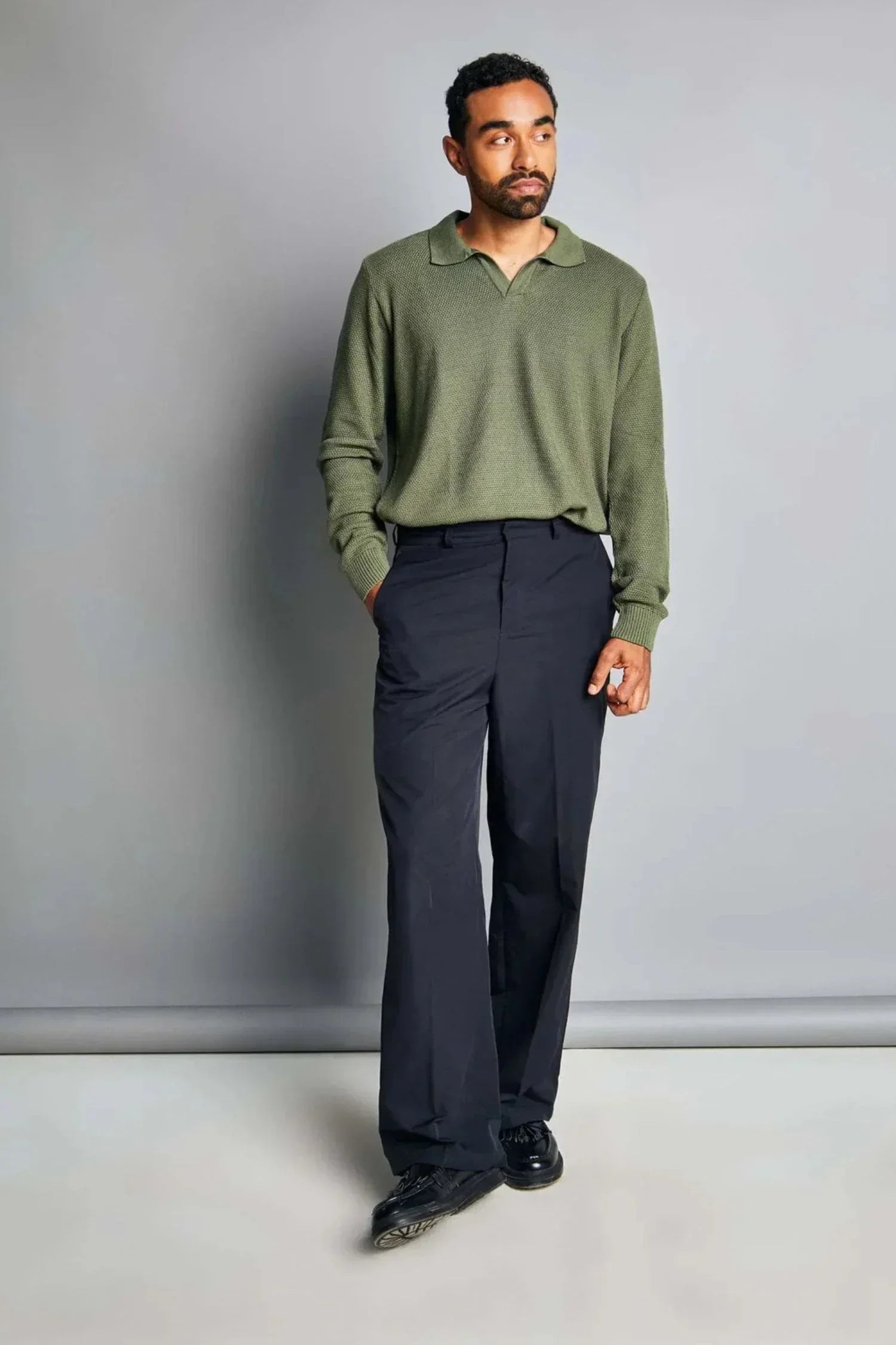 Hombre con suéter verde de punto y pantalón negro, moda casual masculina