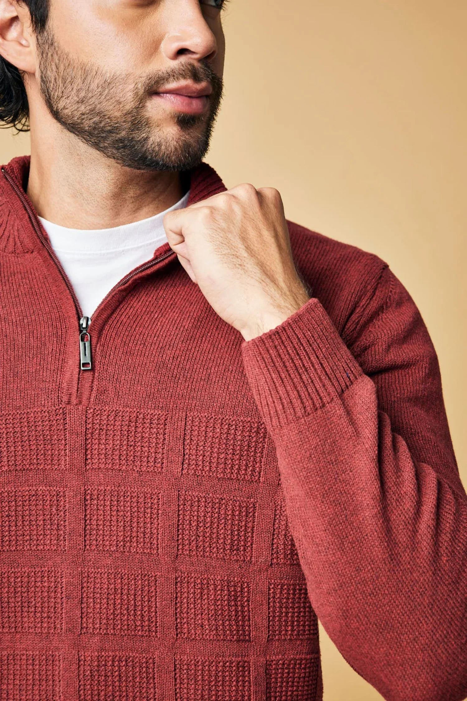 Hombre con suéter tejido de punto rojo ladrillo, cierre corto y textura cuadrada.