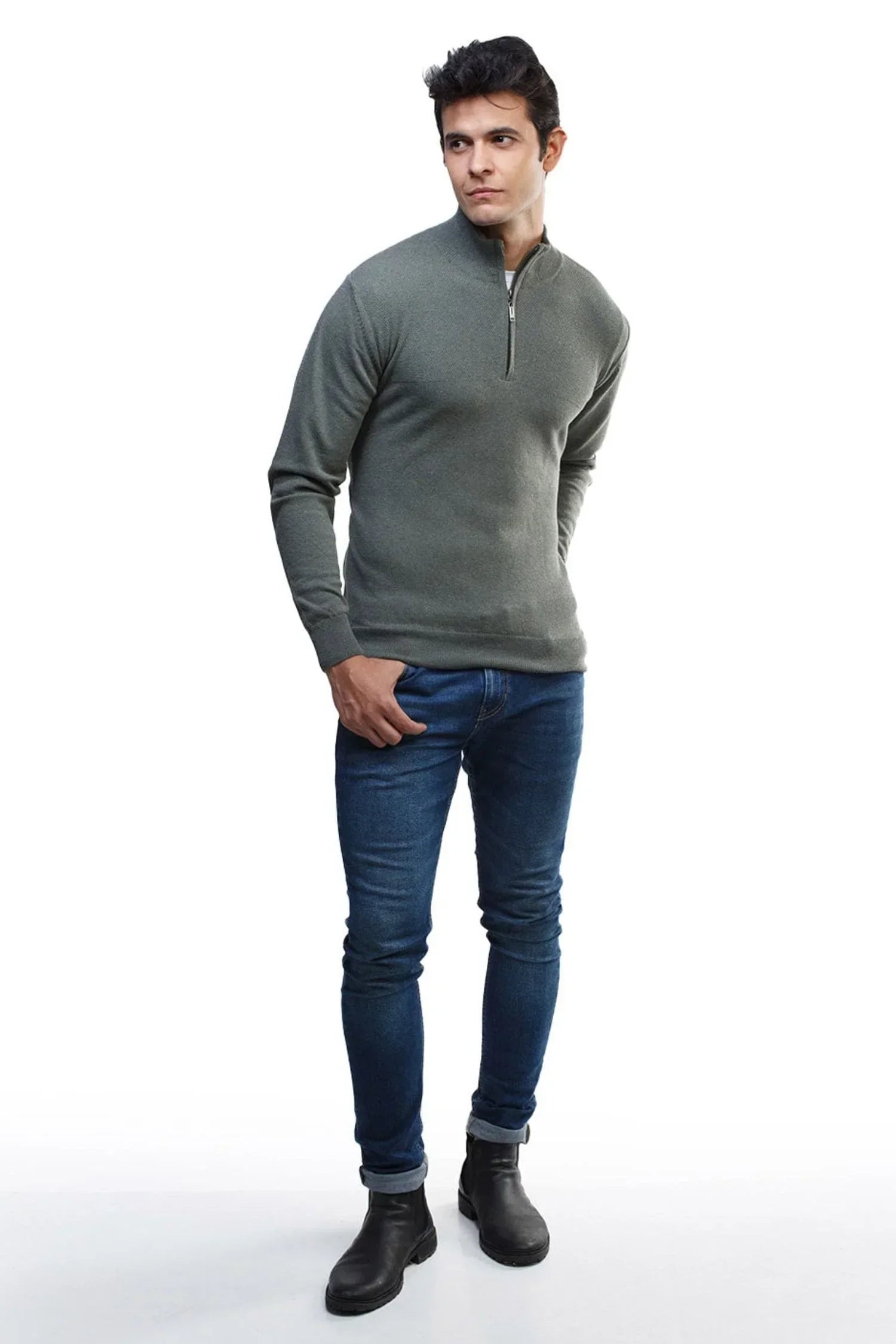 Hombre con suéter tejido gris de cuello alto y cremallera, jeans ajustados y botas negras