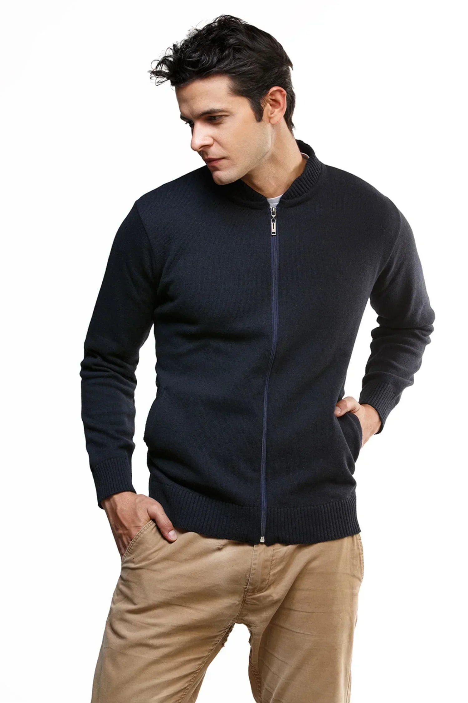 Hombre con chaqueta de punto azul marino y pantalón beige sobre fondo blanco