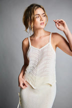 Mujer con blusa tejida blanca de tirantes y falda a juego, estilo moderno y cómodo.