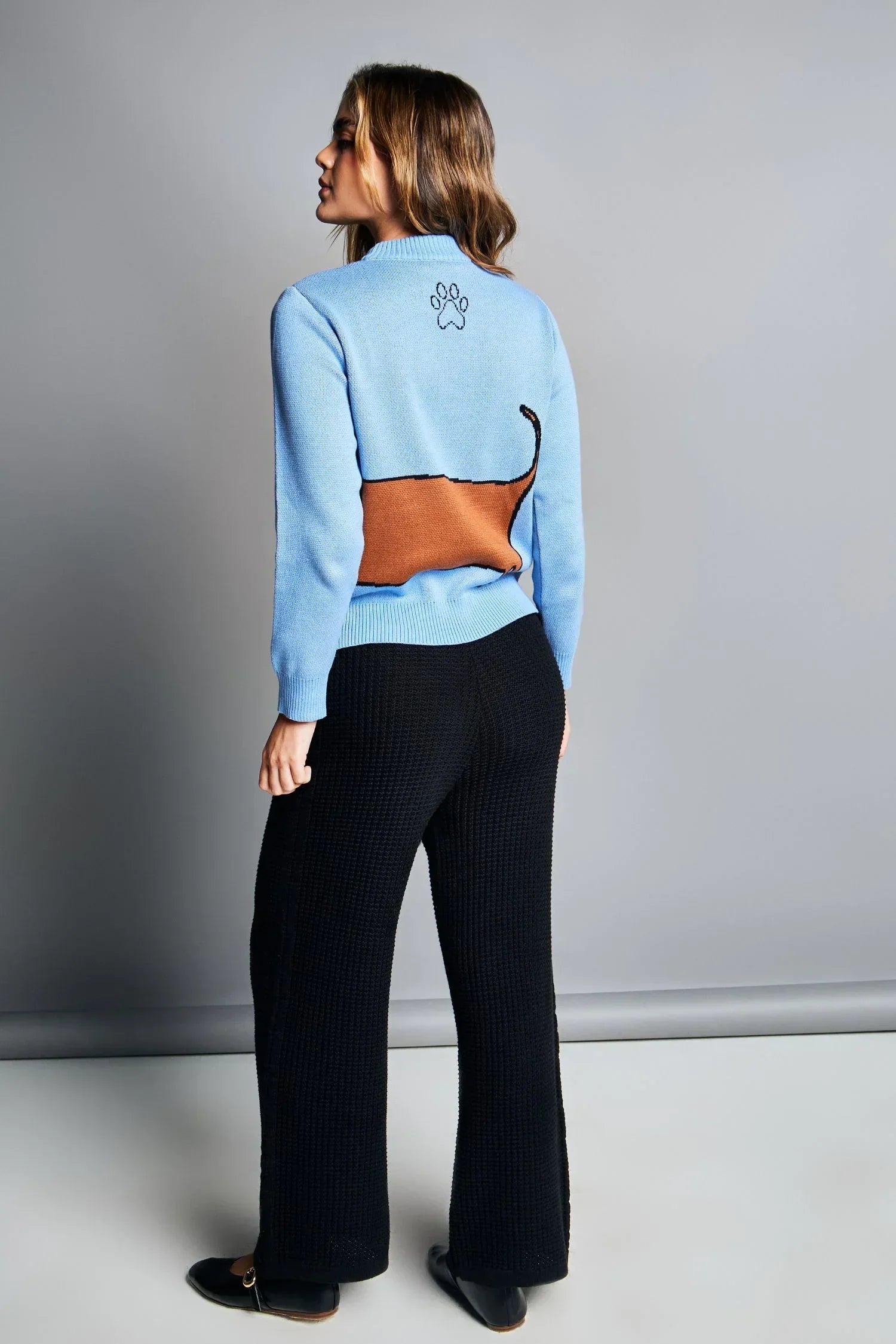 Mujer con suéter azul de punto con diseño de perro y pantalón negro, moda femenina casual