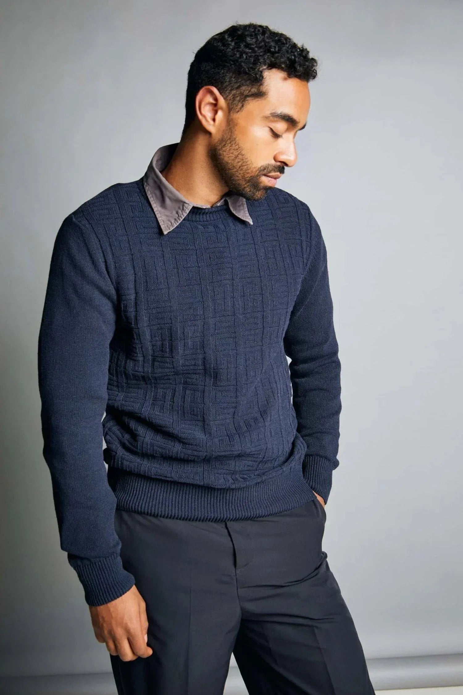 Hombre con suéter azul marino de punto y pantalón oscuro, moda masculina elegante