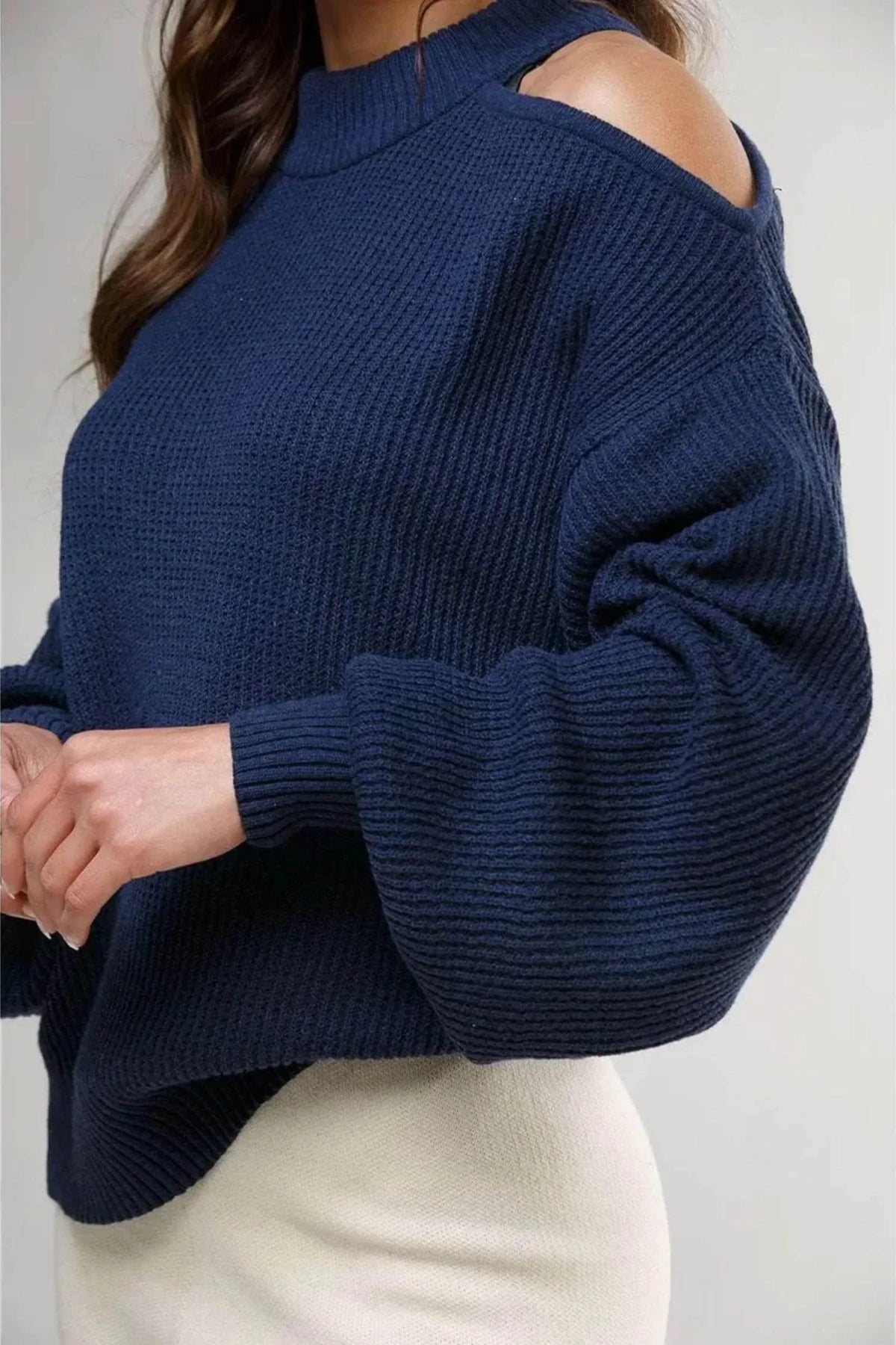 Suéter azul marino para mujer con hombros descubiertos y textura de punto grueso.