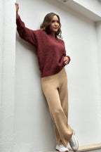 Mujer con suéter burdeos, pantalón beige y zapatillas blancas, estilo casual moderno.
