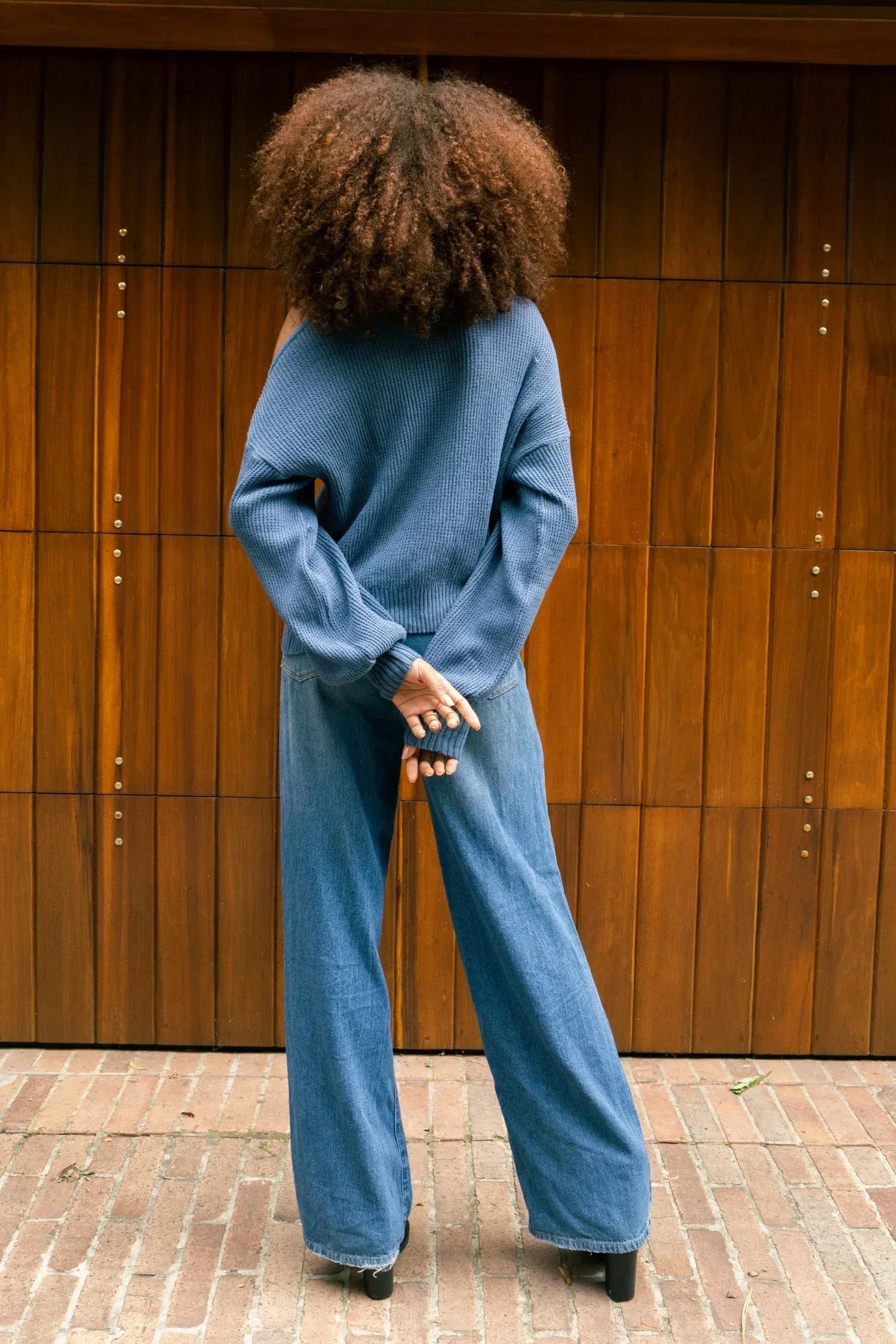 Mujer de espaldas con suéter azul de punto y pantalón de mezclilla, moda casual femenina.