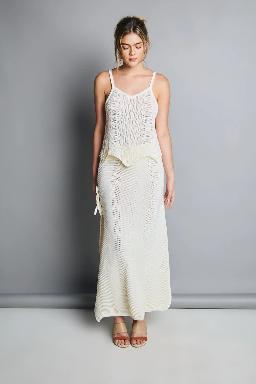 Mujer con conjunto tejido blanco de tirantes y falda larga, moda elegante y cómoda.