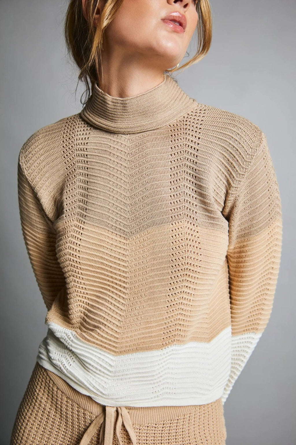 Suéter tejido beige de mujer con cuello alto y detalle blanco en la parte baja