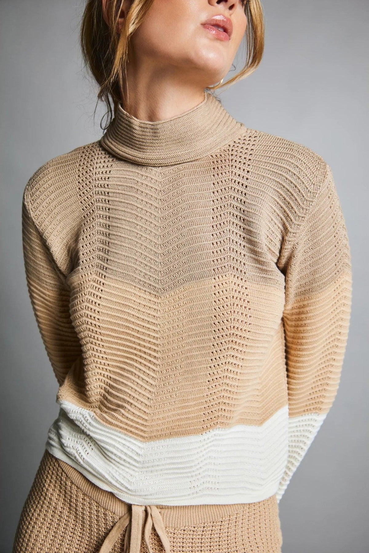 Suéter tejido beige de mujer con cuello alto y detalle blanco en la parte baja