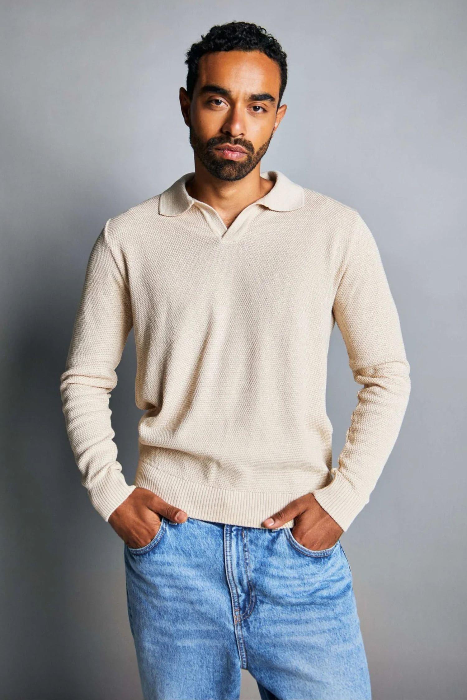 Hombre joven con suéter beige de punto y jeans azules, moda casual masculina elegante