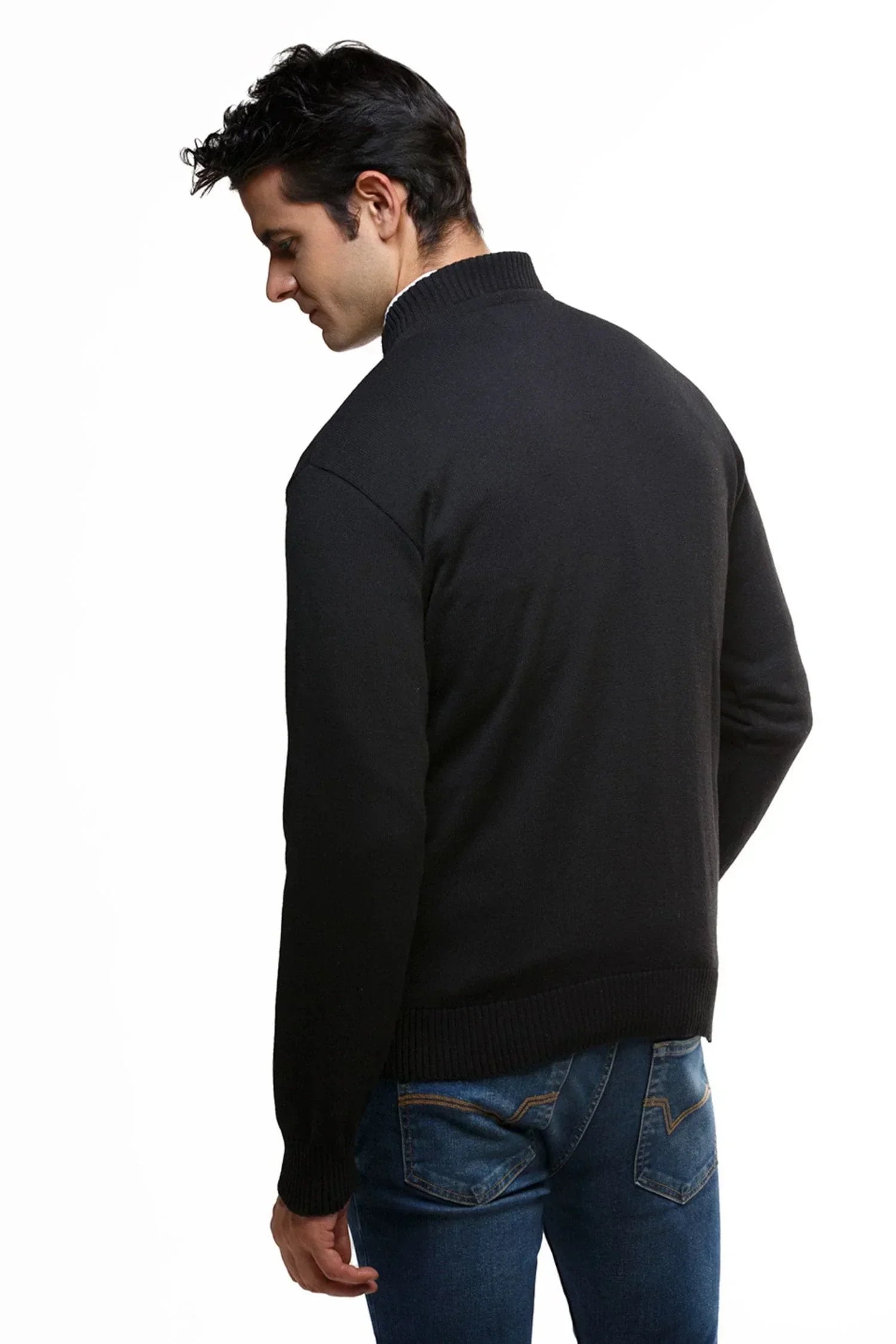 Hombre de espaldas con suéter negro de tejido de punto y jeans azul, fondo blanco