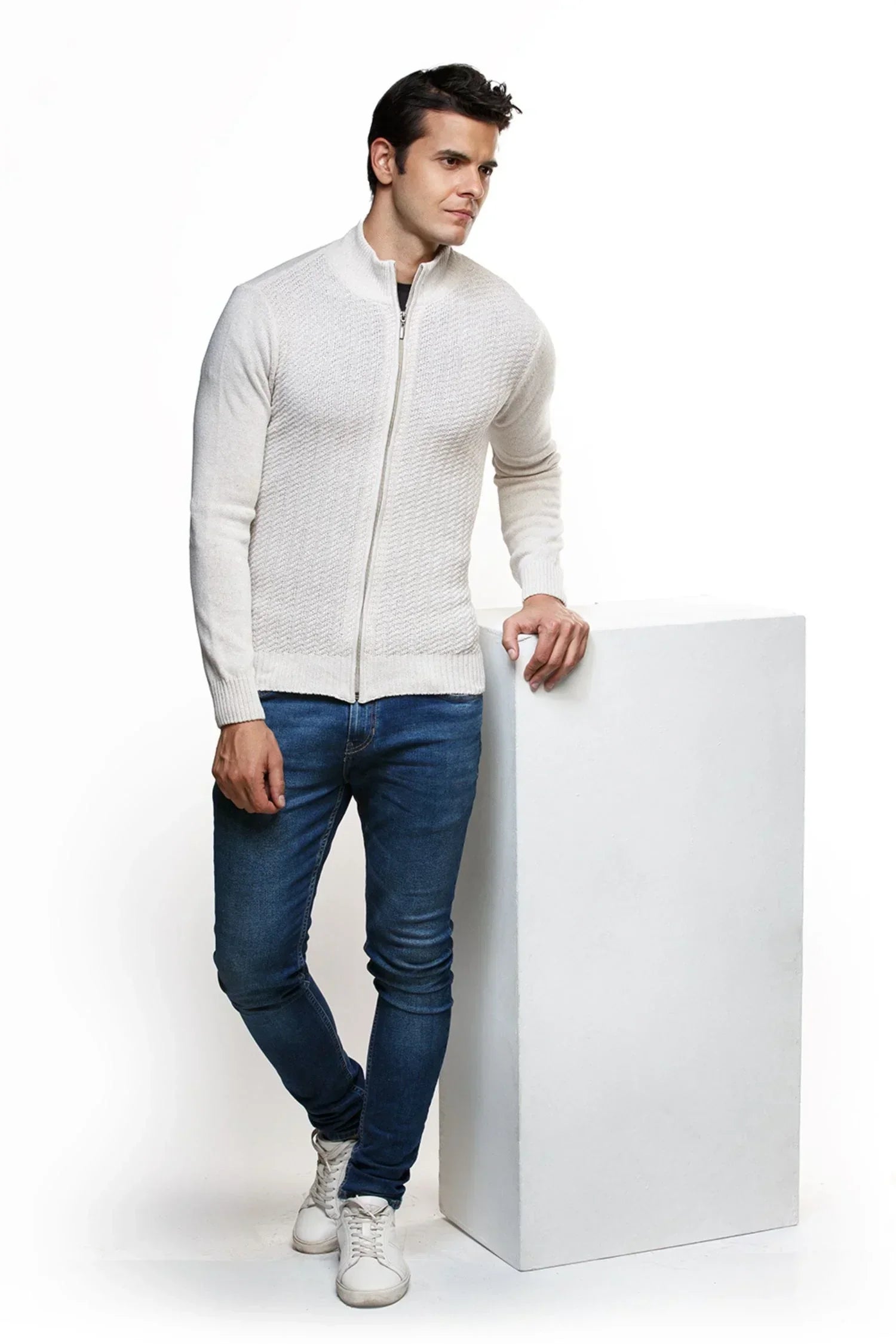 Hombre con chaqueta tejida beige y jeans ajustados, moda casual para hombre.