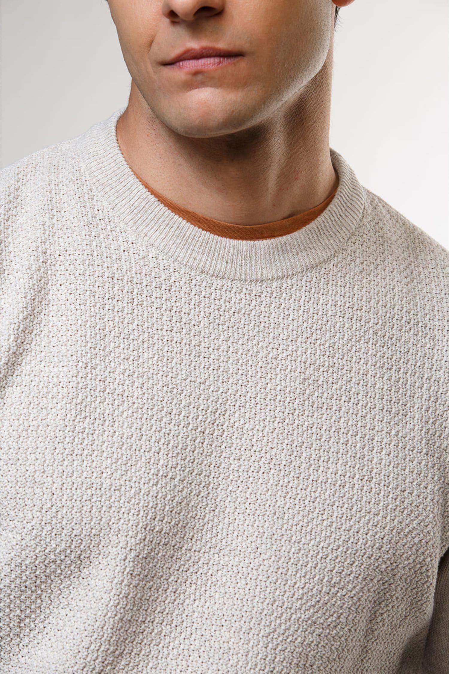 Hombre vistiendo suéter gris claro de punto grueso y camiseta marrón debajo