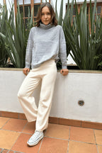 Mujer con suéter gris de cuello alto y pantalón beige de punto, look cómodo y casual