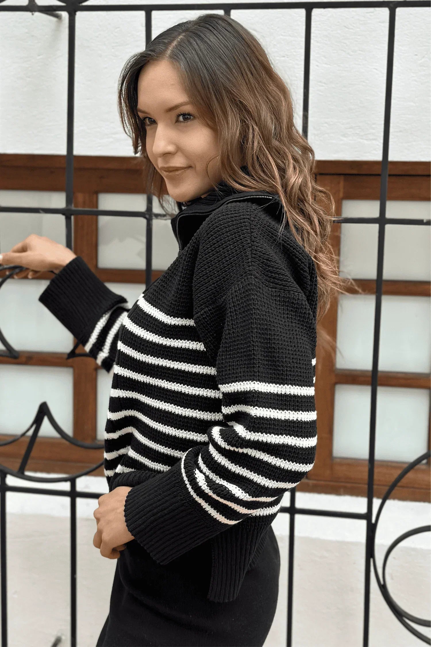 Mujer con suéter tejido de punto negro con rayas blancas, moda casual femenina